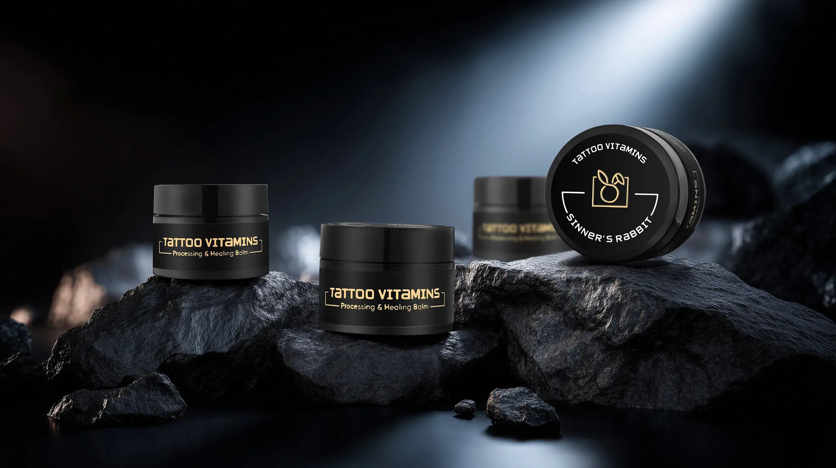Tattoo Vitamins Healing Balm products on dark rocks with a spotlight effect