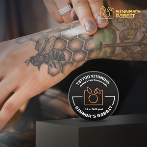 Tattoo Vitamins Box of 24 Tins in half oz, using on a tattooed hand
