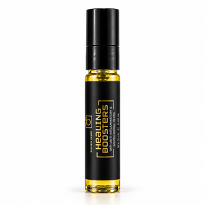 A small cylindrical glass roller bottle filled with yellow oil, featuring a black cap and a black label with gold text that reads 'Healing Boosters' and 'Handmade Hair.' The bottle is centered on a clean white background.